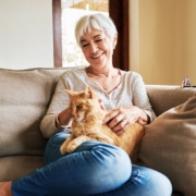 Image of a mature women sitting on couch with an orange cat
