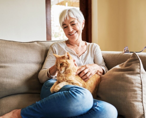 Image of a mature women sitting on couch with an orange cat