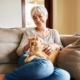 Image of a mature women sitting on couch with an orange cat